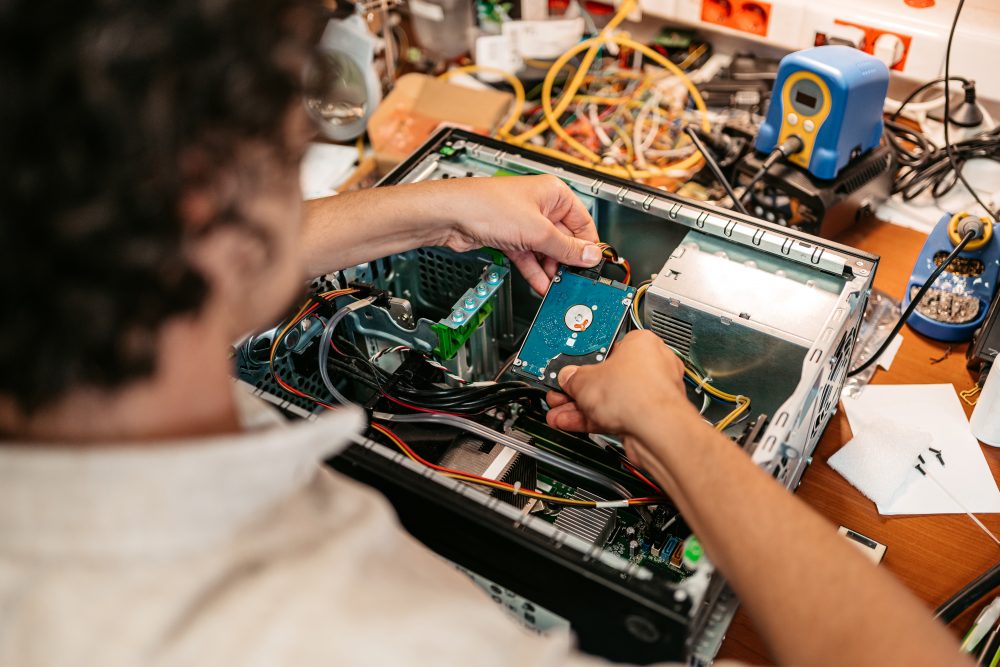 Ein junger Mann baut elektronische Teile in ein Elektronik Gehäuse ein.