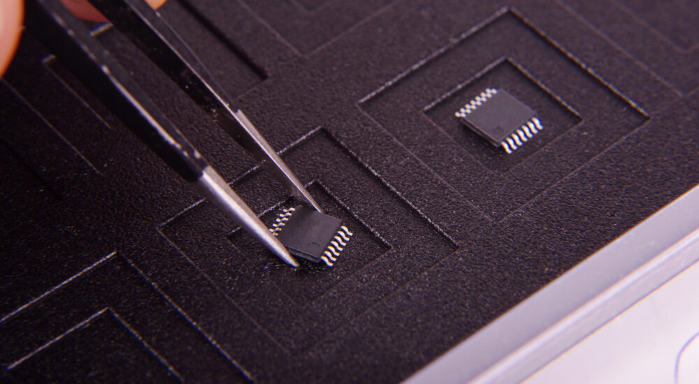 Winziger SMT-Technologie-Elektronikchip-Bauteil und Ingenieur, der ihn mit einer Pinzette hält