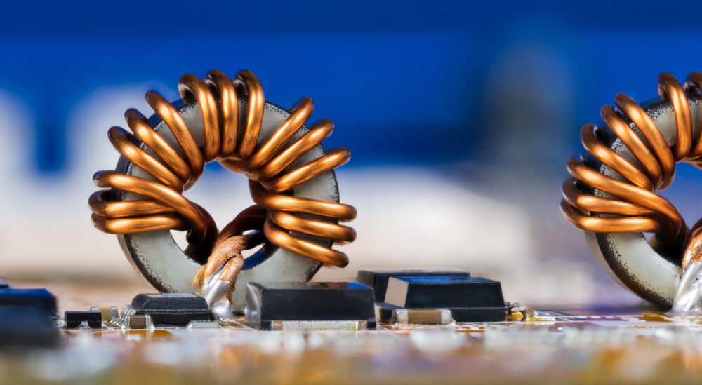 Detailansicht von elektronischen Bauteilen wie Spulen oder Transistoren auf einer Leiterplatte. Freiraum auf einem blauen, verschwommenen Gerät